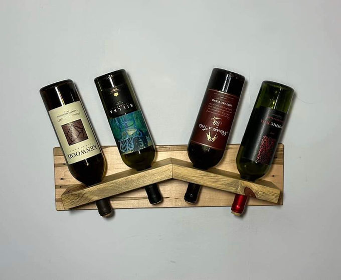 Four bottles resting label-out in a wall-mounted rack of pale salvaged pallet wood.