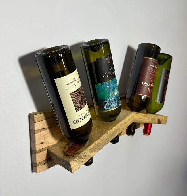 A compact reclaimed-oak wall wine rack mounted on a pale wall, bottles resting at an angle.